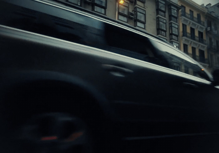 a car driving down a street next to tall buildings