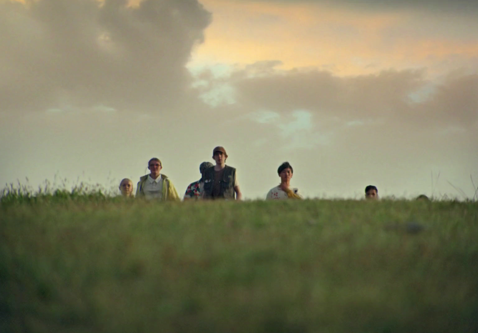 a group of people sitting on top of a lush green field