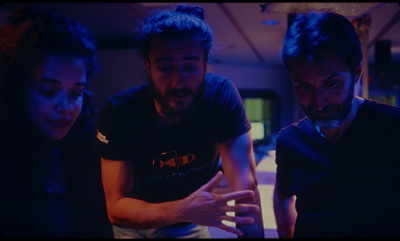 three people looking at a cell phone in a dark room