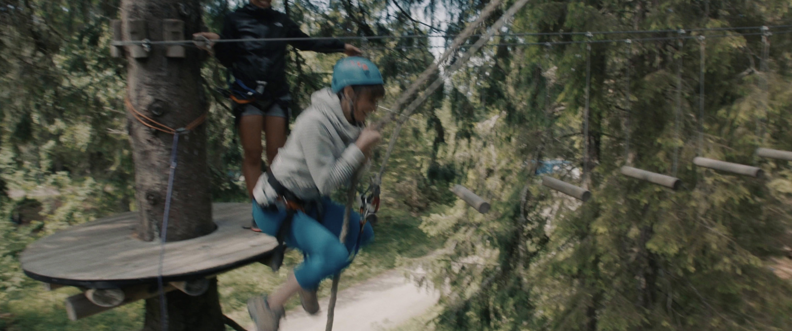 a group of people on a rope course in a forest