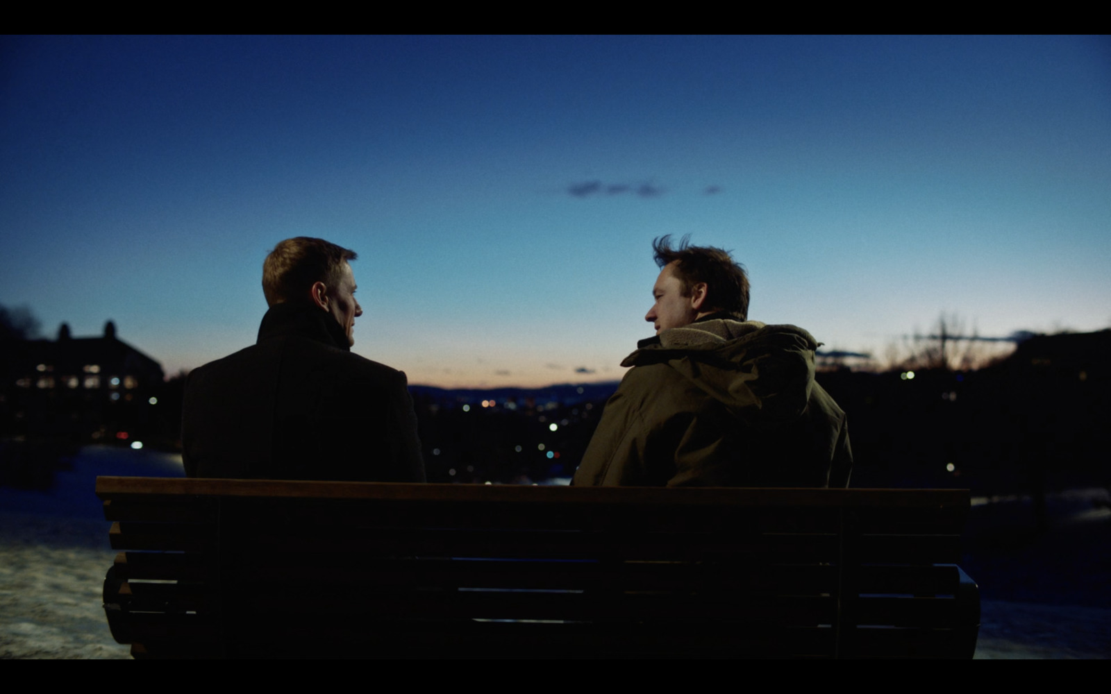 a couple of men sitting on top of a wooden bench