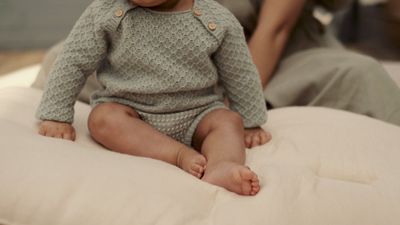 a baby sitting on top of a pillow on a bed