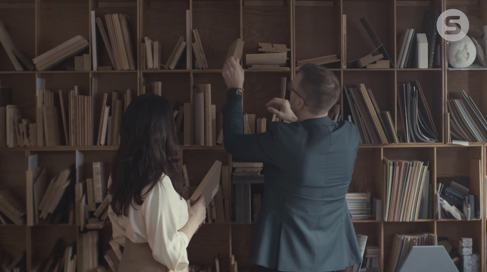 a man and a woman standing in front of a bookshelf