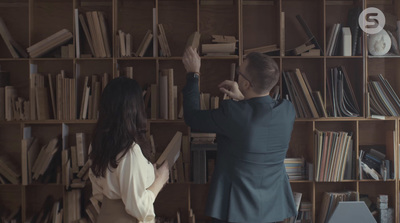 a man and a woman standing in front of a bookshelf