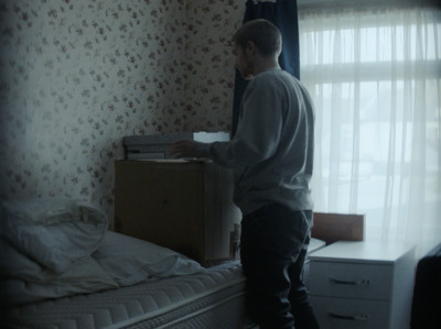 a man standing next to a bed in a bedroom