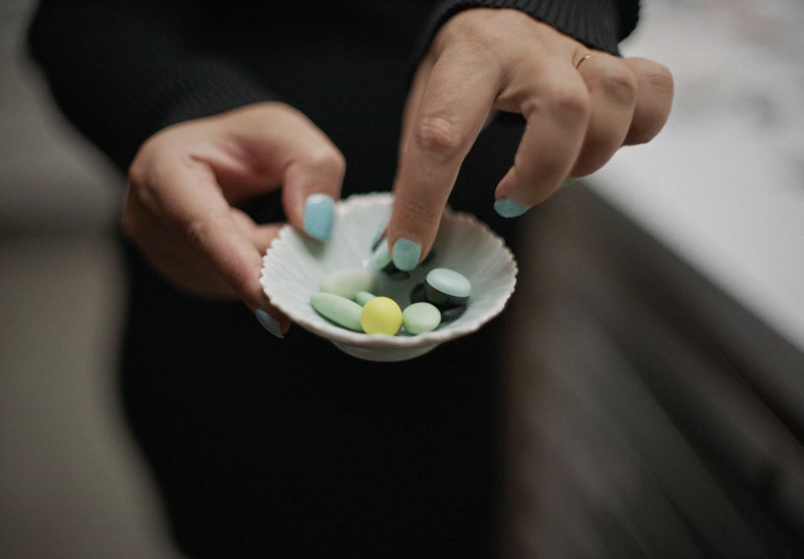 a woman holding a paper bowl filled with pills