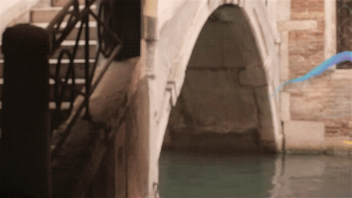 a blue kite flying over a bridge over water