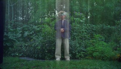 a man standing in front of a lush green forest