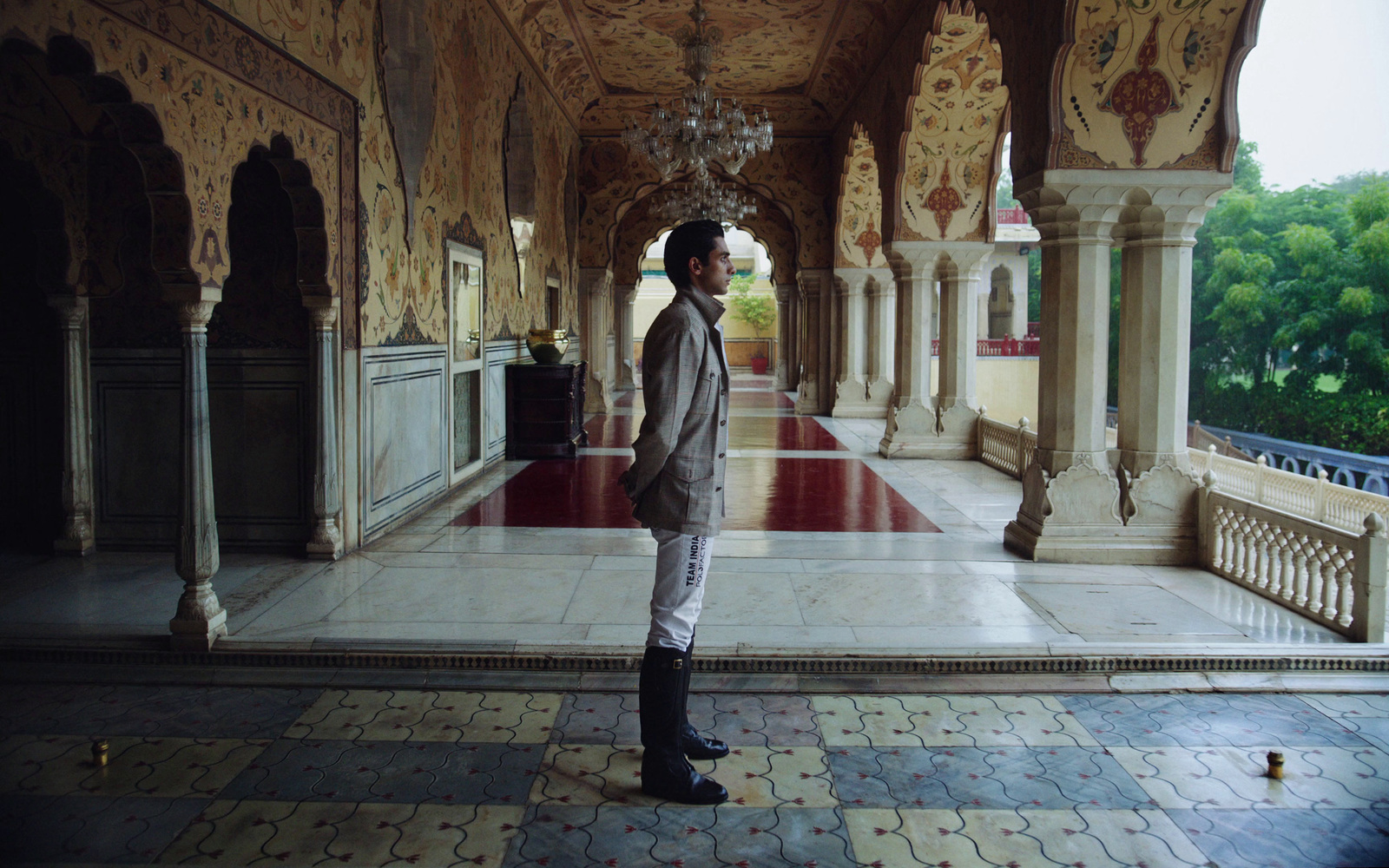 a man standing in a room with a chandelier hanging from the ceiling