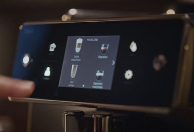 a person is pressing buttons on a coffee machine