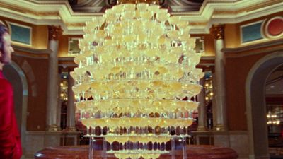 a man standing in front of a tall yellow chandelier