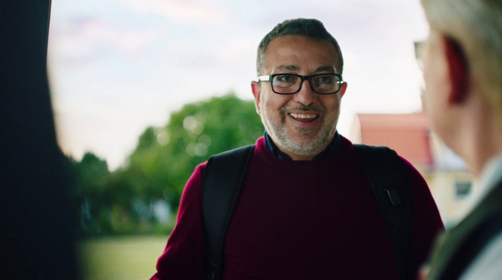 a man wearing glasses talking to a woman