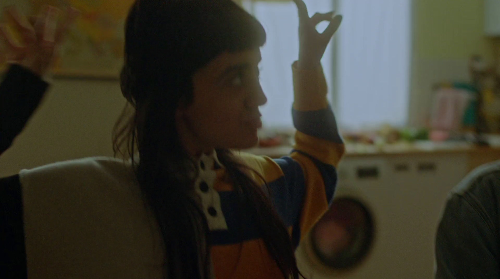 a woman holding up a peace sign in a kitchen