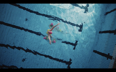 a girl is swimming in a pool with her feet in the water