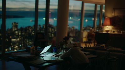 a person sitting at a table with a laptop in front of a window