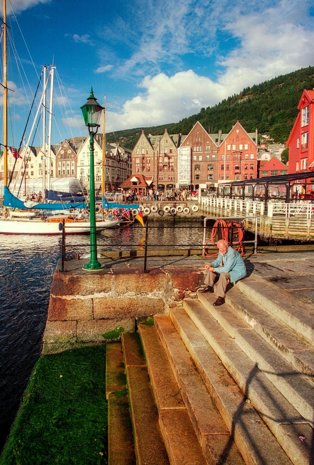 a woman sits on a set of steps near a harbor