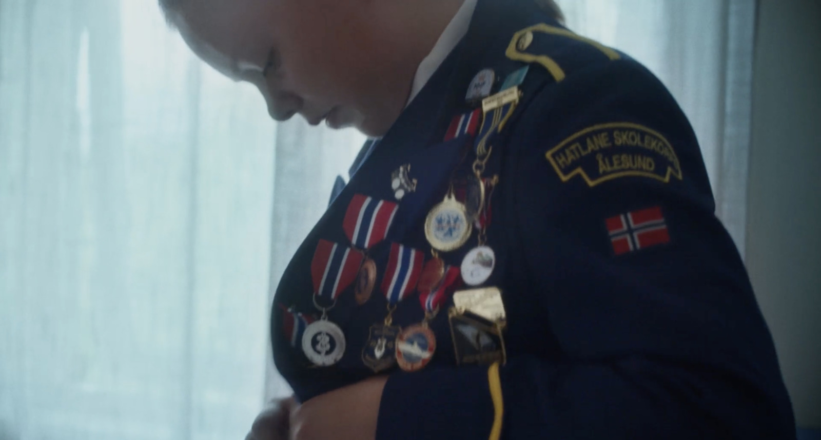 a young boy in a military uniform looking at a cell phone