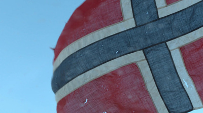 a flag with a cross on it flying in the sky