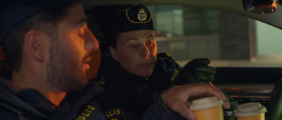 a police officer holding a cup of beer in a car