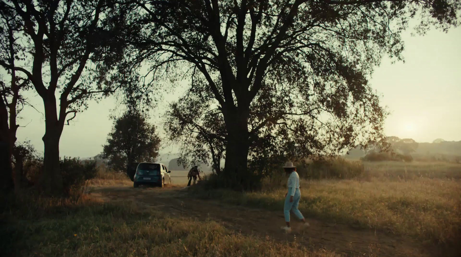 a man walking down a dirt road next to trees