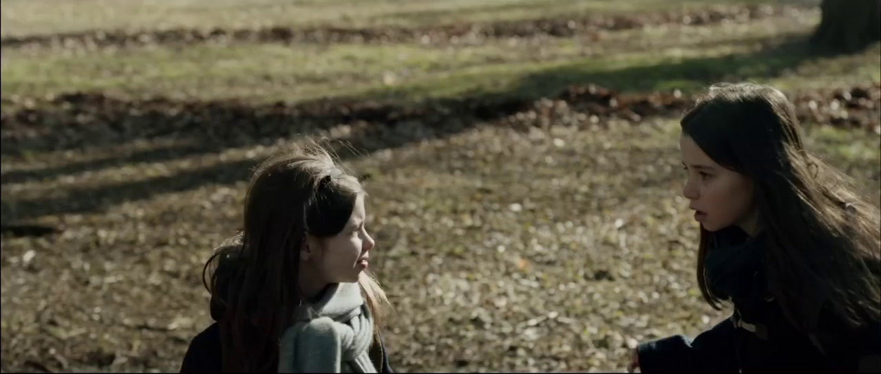 two young girls standing next to each other in a field