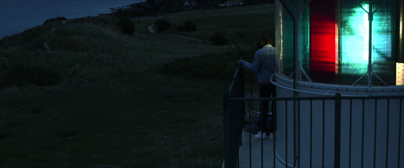 a man standing next to a metal fence at night