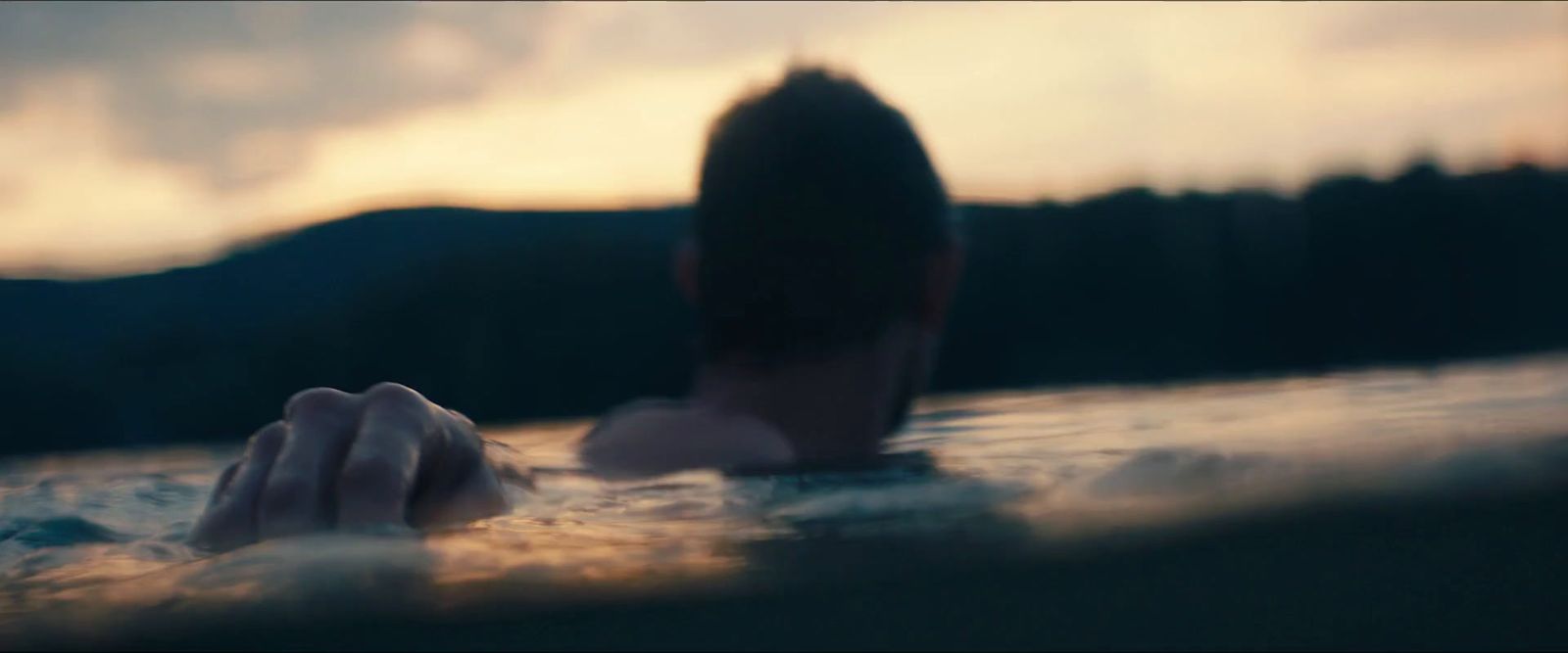 a man in the water with his hand on the edge of the water