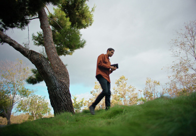 a man standing next to a tree holding a camera