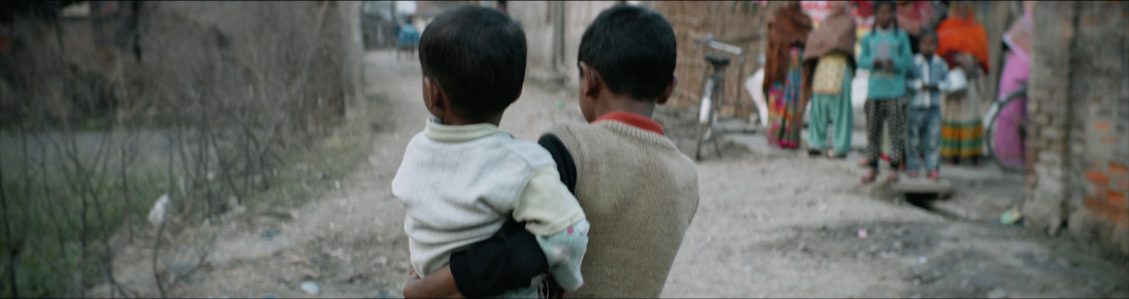 a man carrying a child down a dirt road