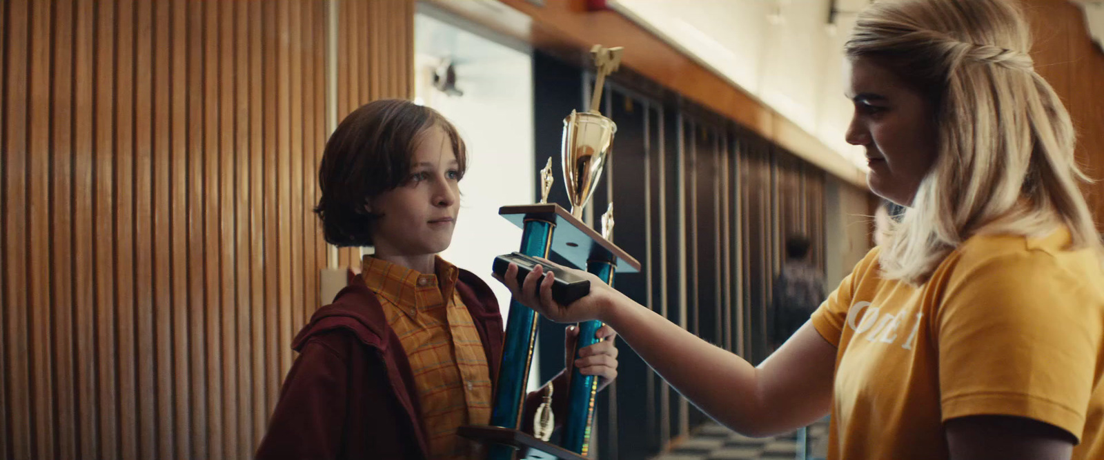 a young girl holding a trophy next to a woman