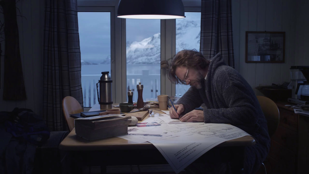 a man sitting at a table writing on a piece of paper