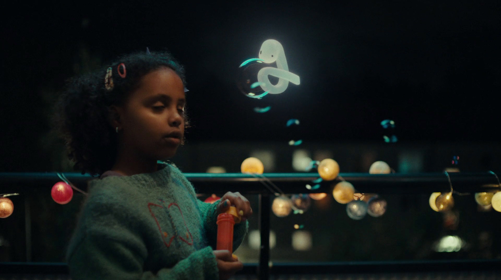 a little girl standing in front of a string of lights