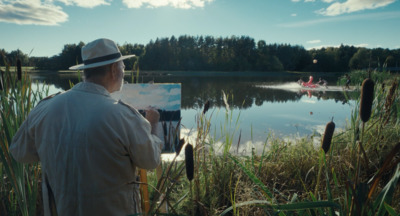 a man in a hat is painting on a canvas