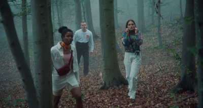 a group of people walking through a forest on a foggy day