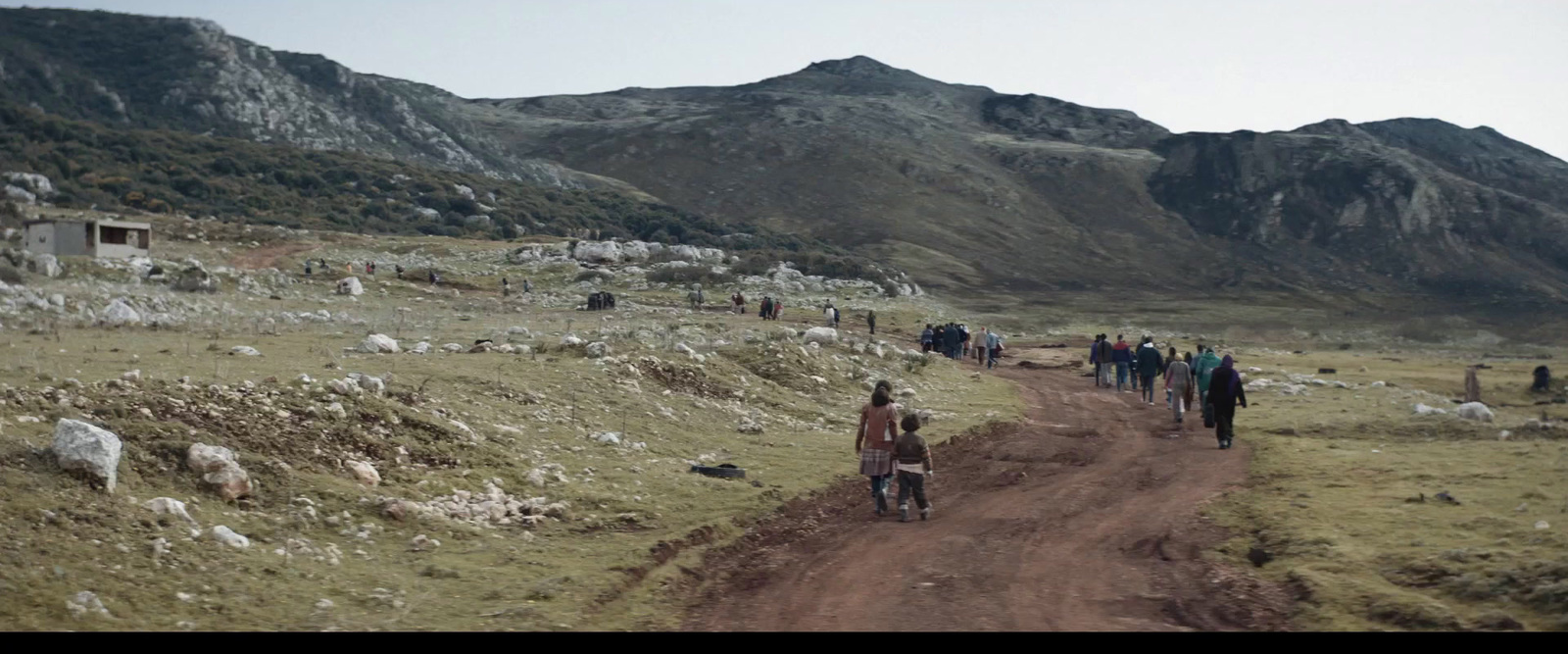 a group of people walking down a dirt road