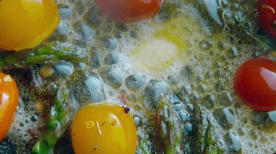 tomatoes and asparagus fry in oil on a pan