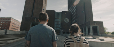 two people walking down a street in front of a large building