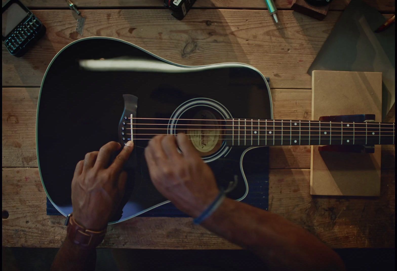 a man playing a guitar on a wooden table