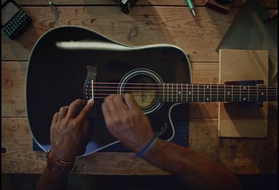 a man playing a guitar on a wooden table