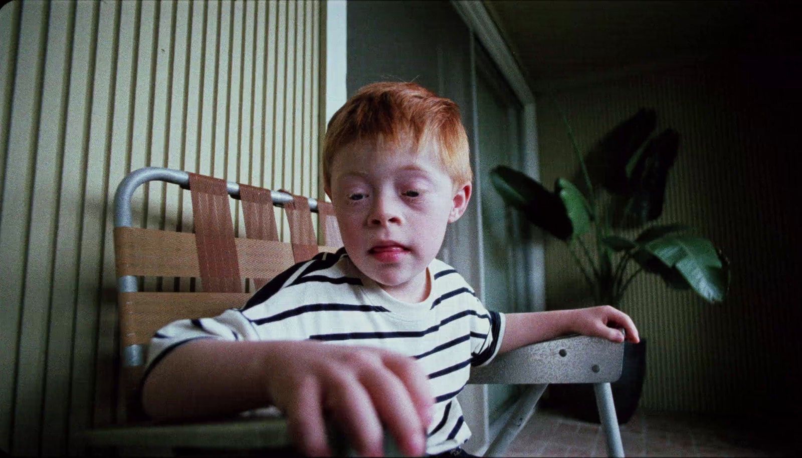 a young boy sitting in a chair with a surprised look on his face