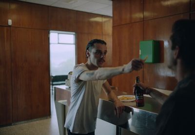 a man standing at a counter with a bottle of beer