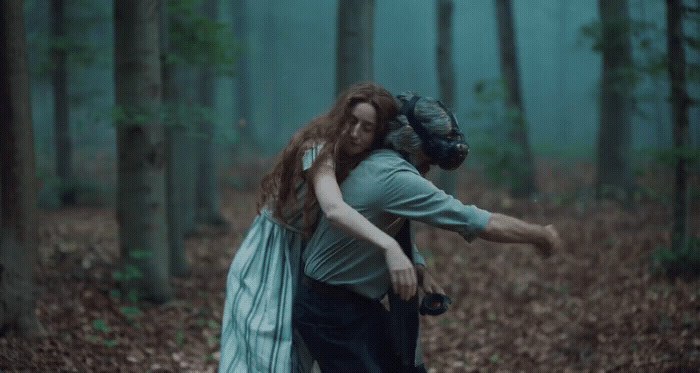 a man carrying a woman in a forest