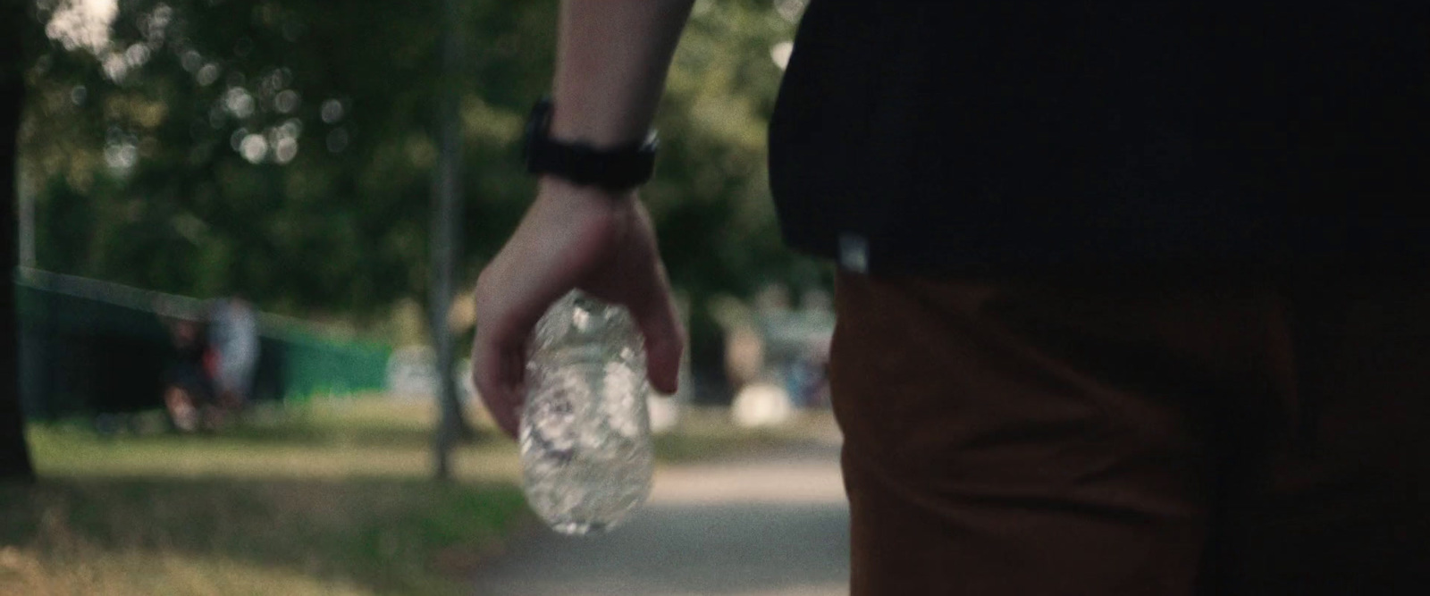 a person walking down a sidewalk holding a plastic bottle