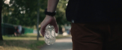 a person walking down a sidewalk holding a plastic bottle