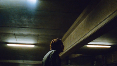 a man standing in a parking garage holding a skateboard