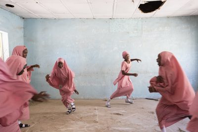 a group of women in pink dresses dancing in a room