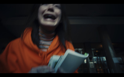 a woman in an orange jacket holding a book