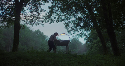 a person standing next to a lamp in a forest