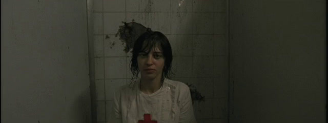 a woman standing in a bathroom with a cross on the floor