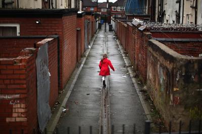 a little girl in a red coat walking down a street